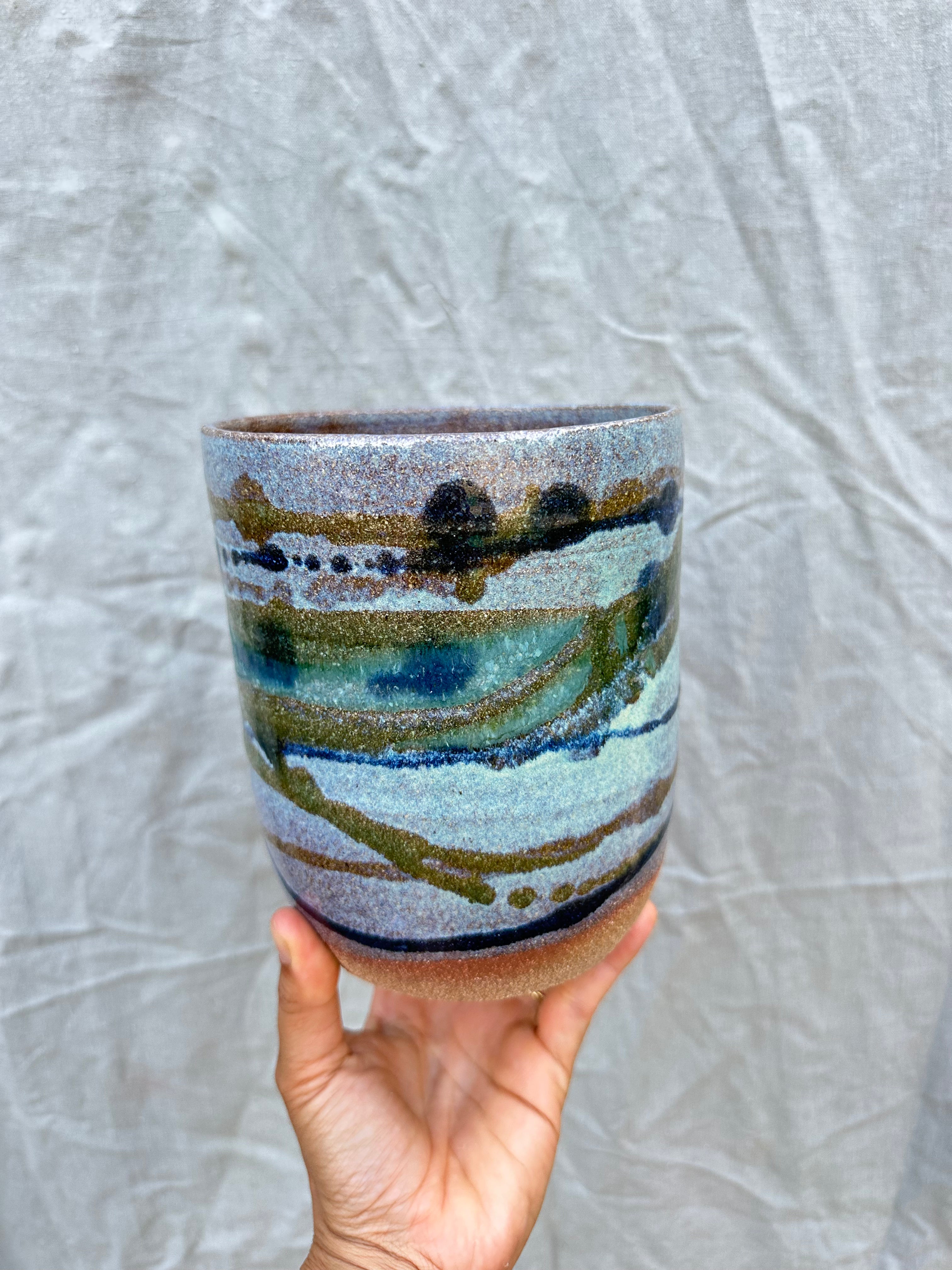 handmade planter pot held against a grey background