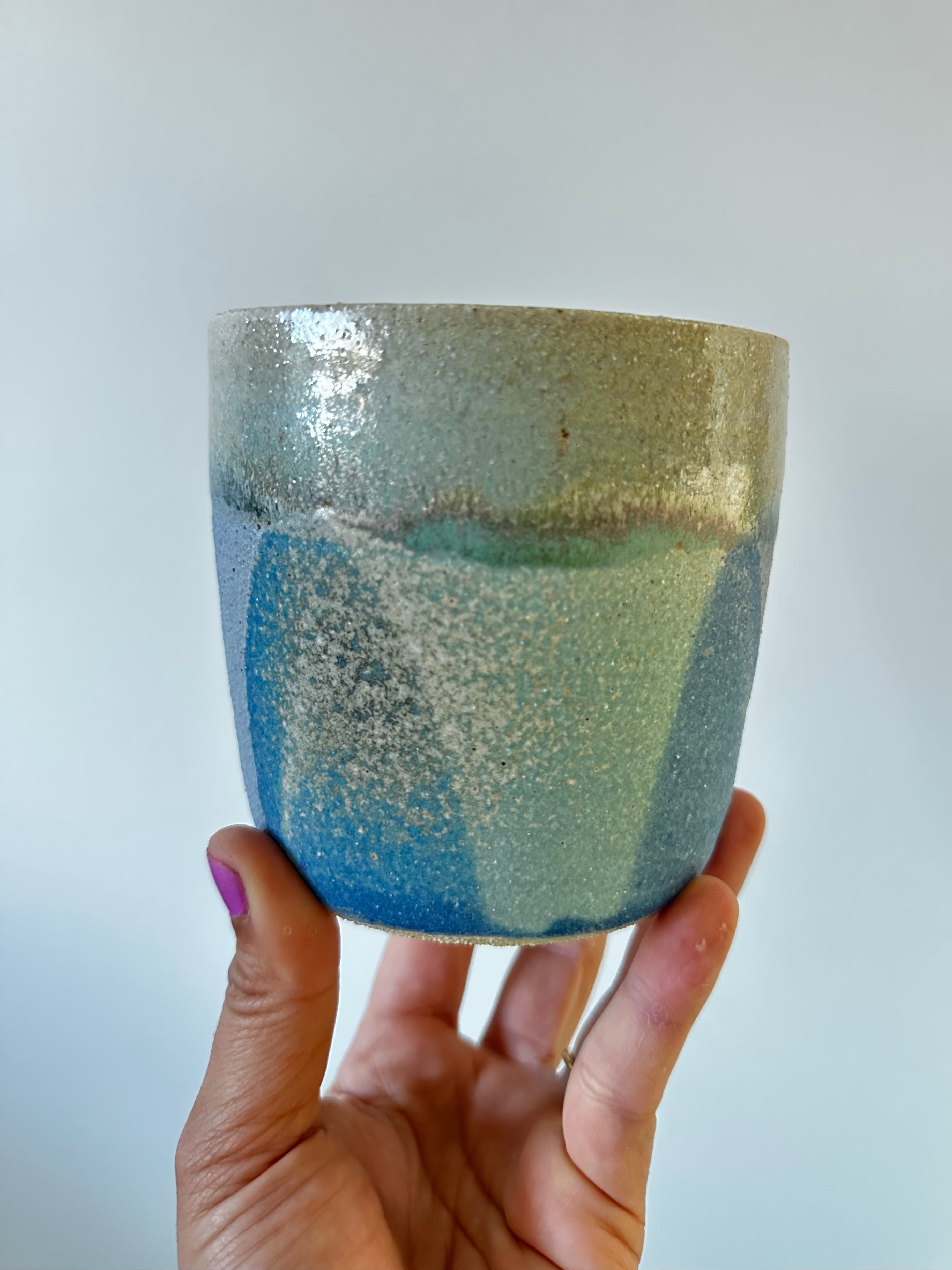 A hand holds up a planter that is blue and green